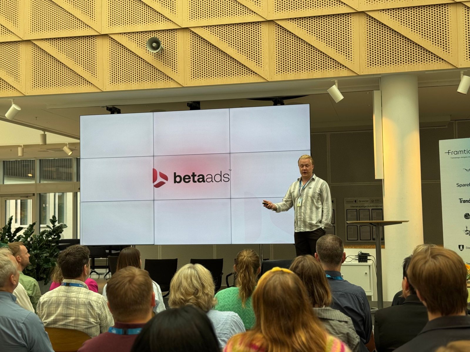 Andreas on stage pitching Beta Ads, with the beta ads logo on the screen